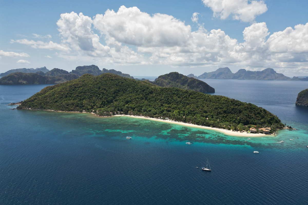 Aerial view of Pangulasian Island Resort in El Nido, Palawan, surrounded by turquoise waters, lush greenery, and a pristine white-sand beach.